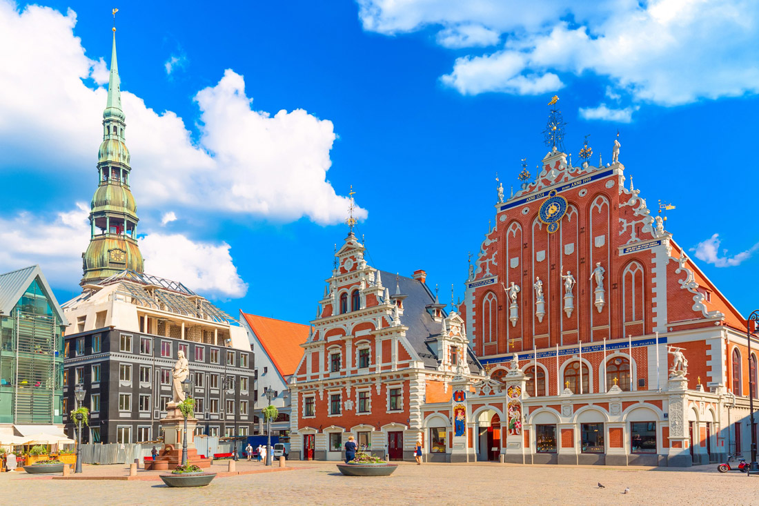Architectural gems in Riga's Old Town: Roland Statue, Blackheads House, and St. Peter's Cathedral against a blue sky.