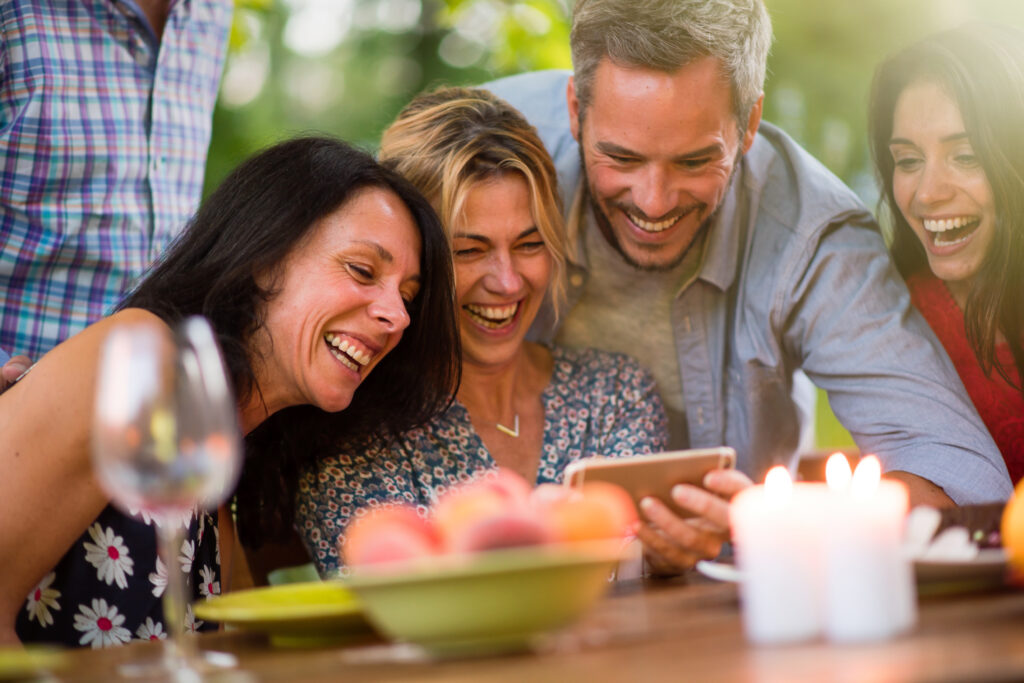 Group of friends laughing together while looking at a smartphone